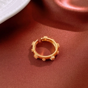 Detail of gold spiral spring ring with delicate flower clusters on silk fabric