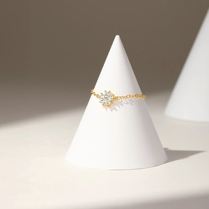 Macro shot of an adjustable gold chain ring featuring a white flower-shaped zircon detail