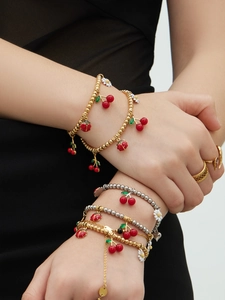Gros plan de bracelets empilés avec breloques émaillées cerise, marguerite et coccinelle