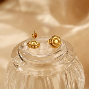 Elegant gold titanium steel floral studs with a sunburst texture on ribbed glass