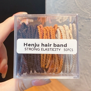 Détail de 50 élastiques à cheveux de tons terreux dans une boîte en acrylique clair