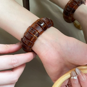 Detail of a chunky resin amber bangle with a vintage tortoiseshell pattern on a model's wrist