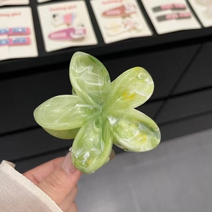 Détail de la pince à cheveux fleur avec texture marbrée verte et blanche brillante