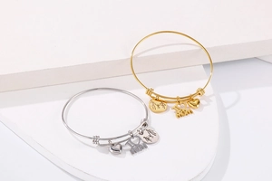 Detail of gold and silver adjustable bangles featuring engraved MOM heart charms and family tags
