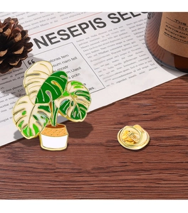 Detail view of cartoon potted plant brooch with green enamel and gold-tone pin back
