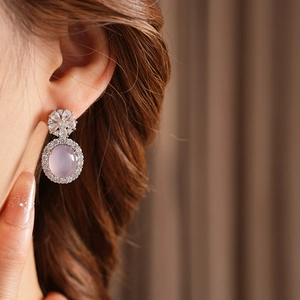 Gros plan de boucles d'oreilles vintage avec pierre mauve et zircons sur un mannequin