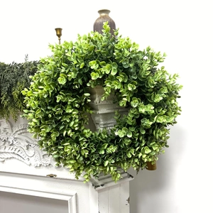 Artificial green money leaf eucalyptus wreath hung on a vintage white fireplace mantel