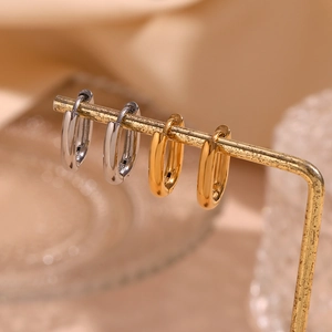 Minimalist oval hoop earrings in polished gold and silver finishes on a display stand