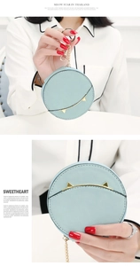 Close-up of light blue round coin purse with metallic cat ears and golden keychain hook