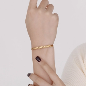 Bracelet jonc doré en acier inoxydable torsadé porté au poignet pour femme