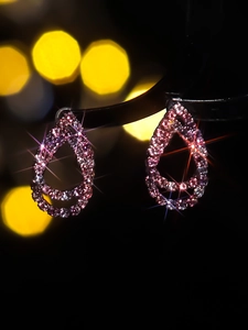 Macro shot of luxury rose pink and white pavé crystal drop earrings with fringe details