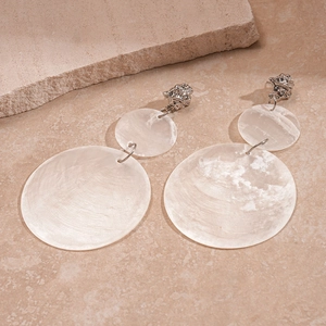 Detail of silver drop earrings with white shell pendants on stone background
