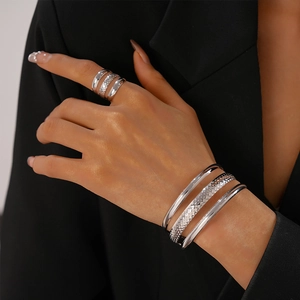 Detail of silver layered metal ring and bracelets set on a model with a dark blazer