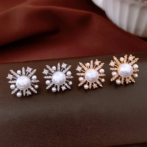 Detailed close-up of starburst pearl earrings with zircon stones in gold and silver