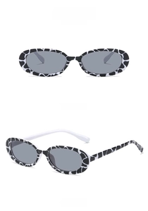 Retro oval sunglasses featuring a black and white cow print frame with dark grey lenses
