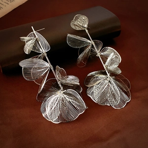 Macro detail of intricate silver woven mesh flower petals and long tassel earrings