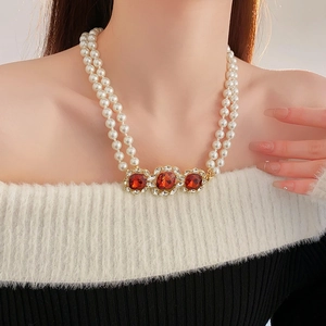 Detail of vintage double-layer pearl necklace with red gemstones and diamond halo