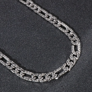 Detail shot of vintage silver Cuban link chain with intricate engraved patterns on metal