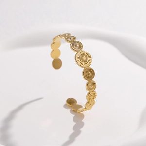 Detail of vintage gold open bangle featuring embossed radial sunburst discs