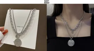 Detail of silver layered necklace with engraved round pendants on a model and card