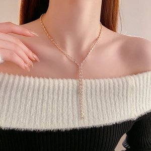 Close-up of gold-tone Y-shaped tassel necklace with crystals on model collarbone