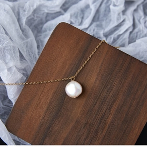 Detail van de platte barokke zoetwaterparel hanger aan 18K vergulde titanium ketting