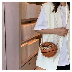 Brown basketball shaped PU leather bag with gold chain strap shown on a model