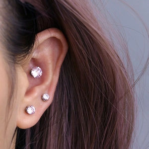 Three pieces of pink zircon magnetic stud earrings in silver settings on a model's ear