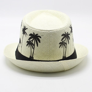 Detail of white straw fedora hat featuring black coconut palm tree patterns and black ribbon band