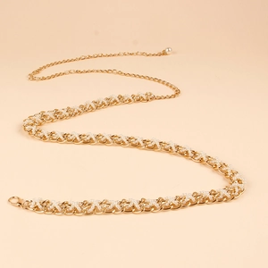 Detailed close-up of woven gold metal waist chain with white pearls and a large pearl charm
