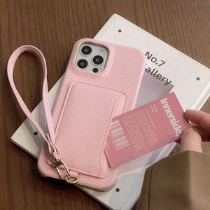 Pink lychee texture leather phone case with card slot and lanyard on a wooden desk