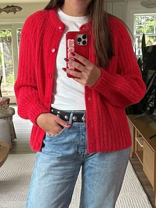 Detail of red knitted button-up cardigan sweater with round neck on female model