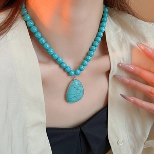 Bohemian turquoise beaded necklace with teardrop stone pendant worn by a model