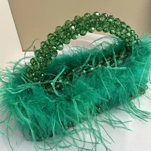 Close-up of green beaded evening handbag with luxury ostrich feather trim and handle