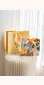 Detail of yellow flower gift bags with elegant ribbons on artistic white paper pedestals