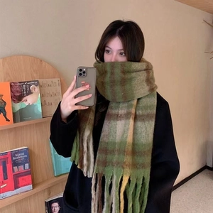Macro detail of soft green and brown plaid mohair scarf with fringe trim and texture
