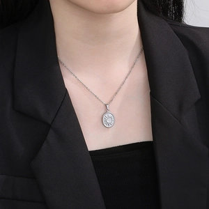 Detailed view of an oval celestial sunburst pendant on a silver-toned metal chain necklace