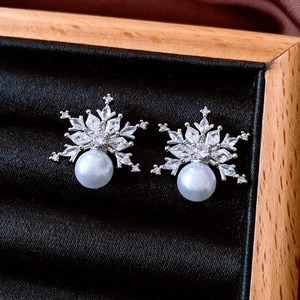 Detail shot of silver snowflake earrings with cubic zirconia and a white pearl drop