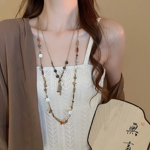 Dettaglio di collana multistrato vintage con nappe a moneta e perline miste sulla modella