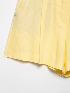 Close-up of light yellow shorts featuring natural linen texture and side seam detail