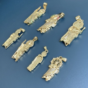 Gold St Jude necklaces with sparkling cubic zirconia on a textured blue surface