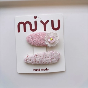 Close-up of pink fabric bow hair clips with lace flower detail on display card