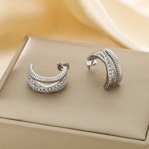 Détails macro des boucles d'oreilles C argentées avec zircons sur fond de satin