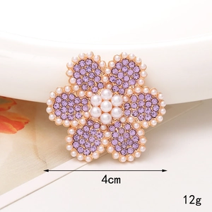 Macro d'une broche tournesol de 4cm avec strass mauves et perles blanches