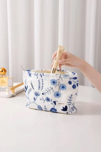 Détail de la pochette en lin blanc avec broderie de marguerites bleues et fermeture éclair