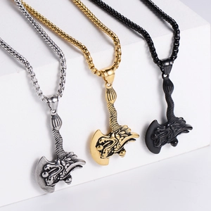 Dragon relief ax pendants in gold, silver, and black colors on white stone display