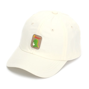 Detailed close-up of a cute green dinosaur rubber patch on a beige cotton kids baseball cap