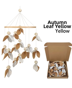 Detail of baby bed mobile with autumn yellow felt leaves and wood beads in gift box