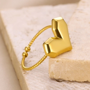 Macro detail of a 18k gold heart ring with twisted rope band on stone decor