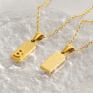 Minimalist gold stainless steel square pendant necklace with initial B on ice-textured background